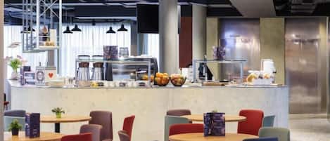 Un café moderne avec un comptoir central, un espace salon et du matériel de cuisine visible.