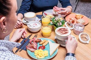 A breakfast setting with a plate of eggs, bacon, toast, and fruit, along with coffee and juice. - Ibis Styles Bern City (Berne)