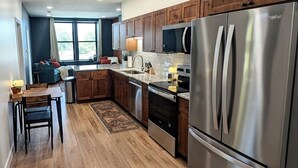 A modern kitchen with wooden cabinets, stainless steel appliances, and a dining area with a table and chairs.