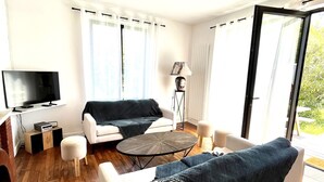 En moderne stue med et fladskærms-tv, to sofaer, et sofabord og en lampe.