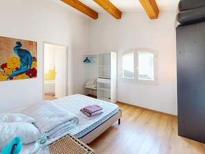 Una camera da letto con un letto, un armadio, una finestra e un quadro appeso al muro.