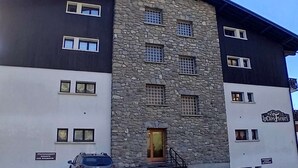Een gebouw met twee verdiepingen, een gevel van natuursteen en een zwart-wit exterieur. Op de voordeur staat een bord met de tekst 