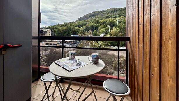 A balcony with a table and two chairs, overlooking a hilly landscape with a ski lift. - Studio Cabin 5 pers, Parking, Near Slopes (Briançon)