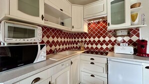 A compact kitchen with white cabinets, a microwave, a toaster, and a red coffee maker. - Studio Cabin 5 pers, Parking, Near Slopes (Briançon)