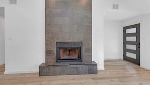 A modern interior with a fireplace, white walls, and a wooden floor. - Hot Tub | Speakeasy | Basketball Court | Sleeps 12 (Cedar Park)