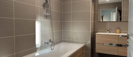 A modern bathroom with a freestanding bathtub, a vanity with a mirror, and a shower area.