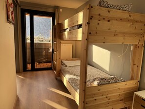 A wooden bunk bed room with a sliding glass door leading to an outdoor balcony.