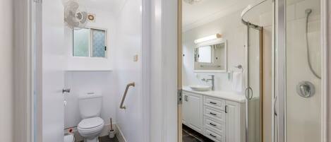 Een moderne badkamer met toilet, douche en hygiëneschuimer.
