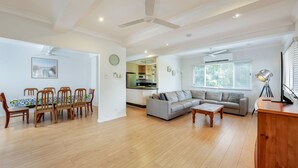 A spacious living area with a dining table, sofa, and a kitchen in the background.