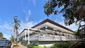 A two-story building with a flat roof and a covered outdoor seating area.