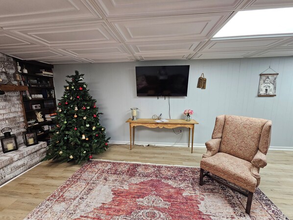 A living room with a Christmas tree, a TV, a patterned armchair, and a wooden coffee table.