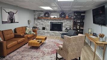 Una sala de estar con chimenea, un sofá, una mesa de centro y un televisor.