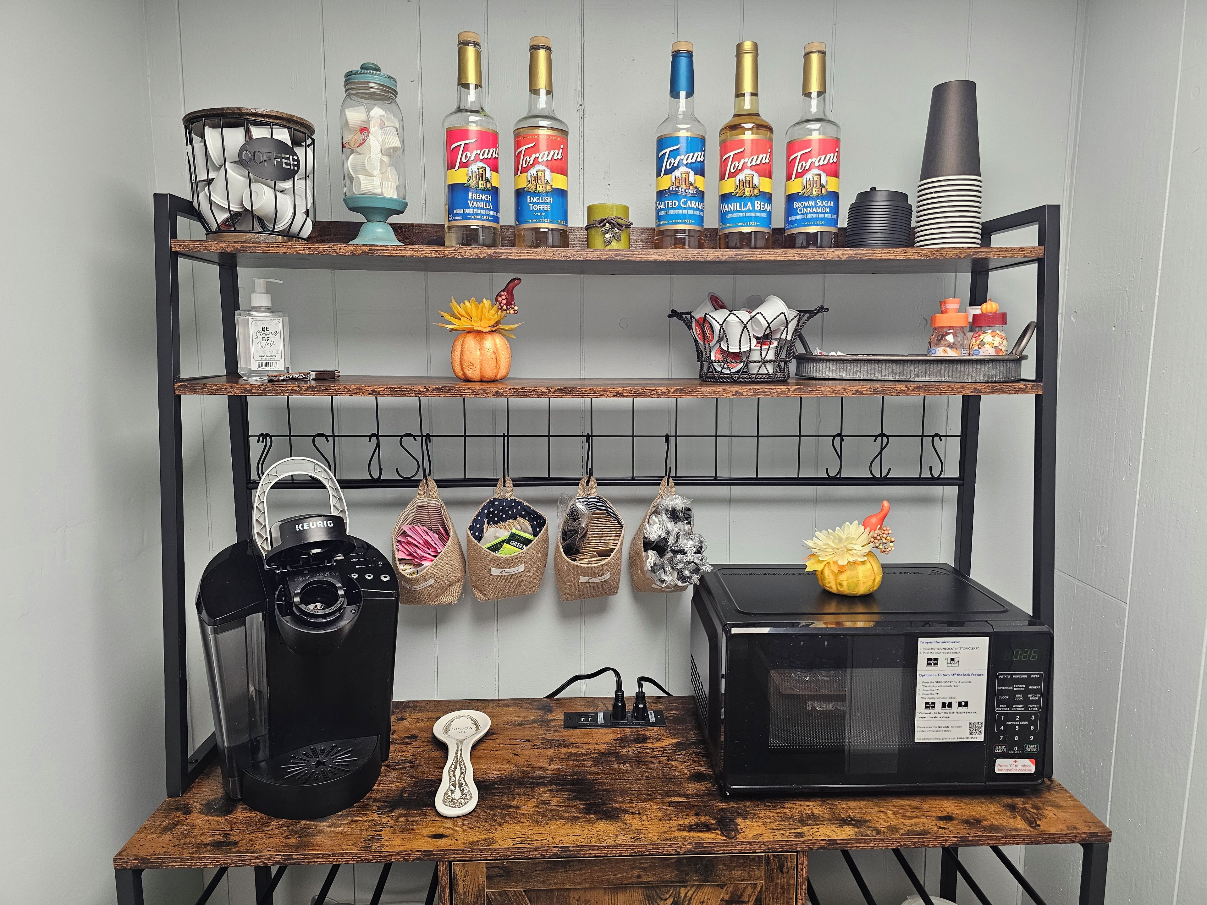A kitchen with a coffee maker, a microwave, and shelves with bottles and kitchenware.