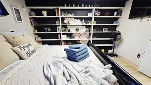 Une chambre à coucher avec un lit, une bibliothèque et un ventilateur.