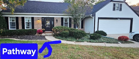A two-story house with a front porch, a garage, and a well-maintained lawn.