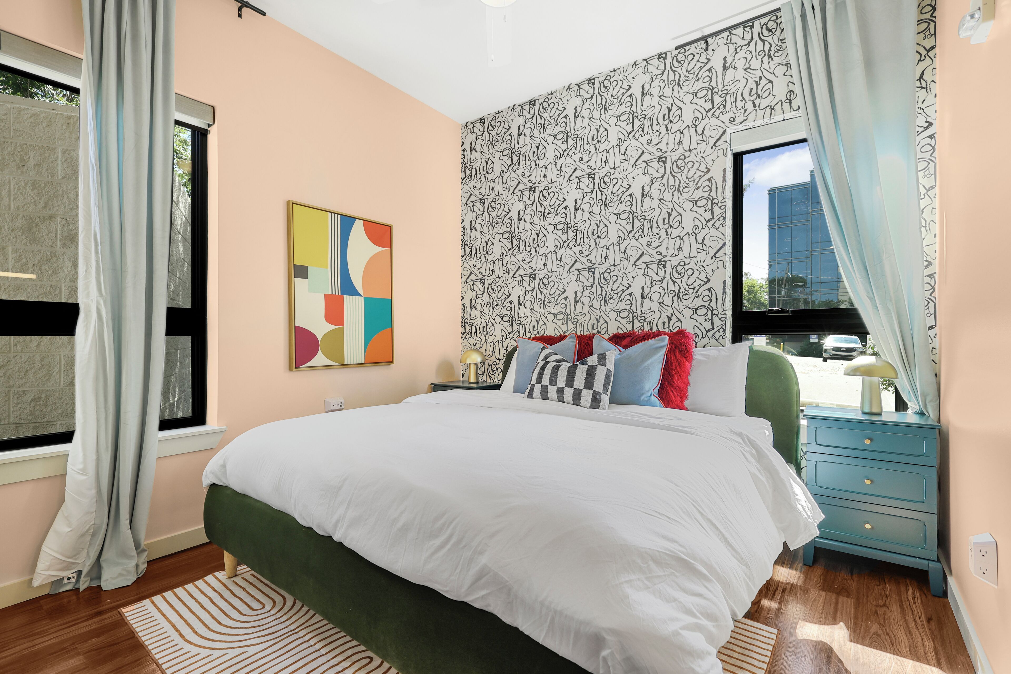 Une chambre à coucher avec un grand lit, une table de chevet, une commode et une fenêtre avec des rideaux.