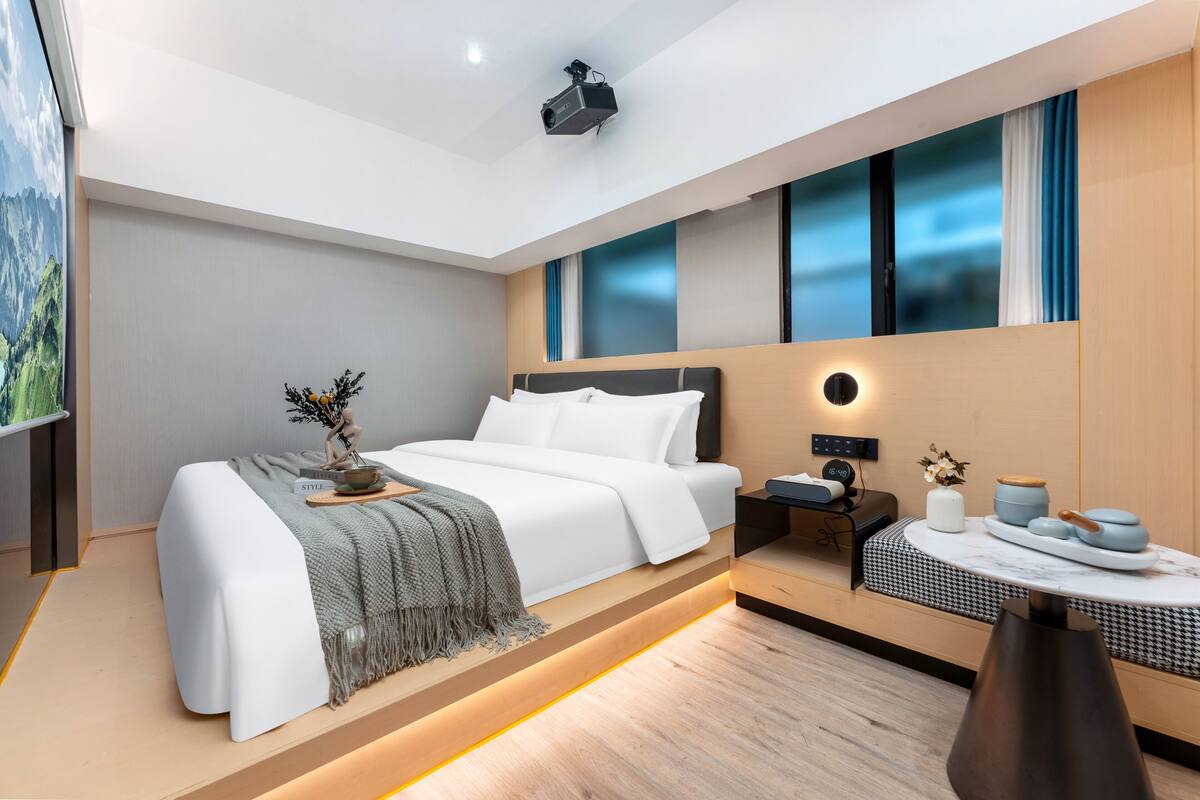 Une chambre d’hôtel moderne dotée d’un grand lit, d’une table de chevet et d’un petit coin salon avec une table et des chaises.