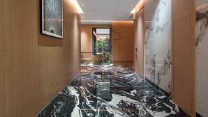 A hallway with a marble floor, wooden walls, and a framed artwork.