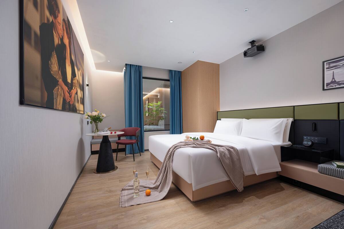 Une chambre d’hôtel moderne, dotée d’un grand lit, d’un bureau, d’une chaise et offrant une vue sur l’extérieur.