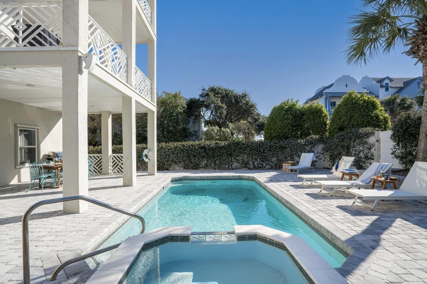 A swimming pool with lounge chairs and a covered seating area.