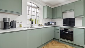 Una cocina moderna con armarios verdes, microondas, cafetera y lavavajillas.
