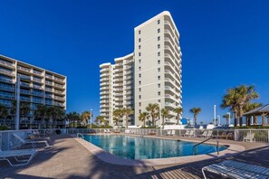 Un hôtel doté d’une piscine, de plusieurs balcons et de palmiers.