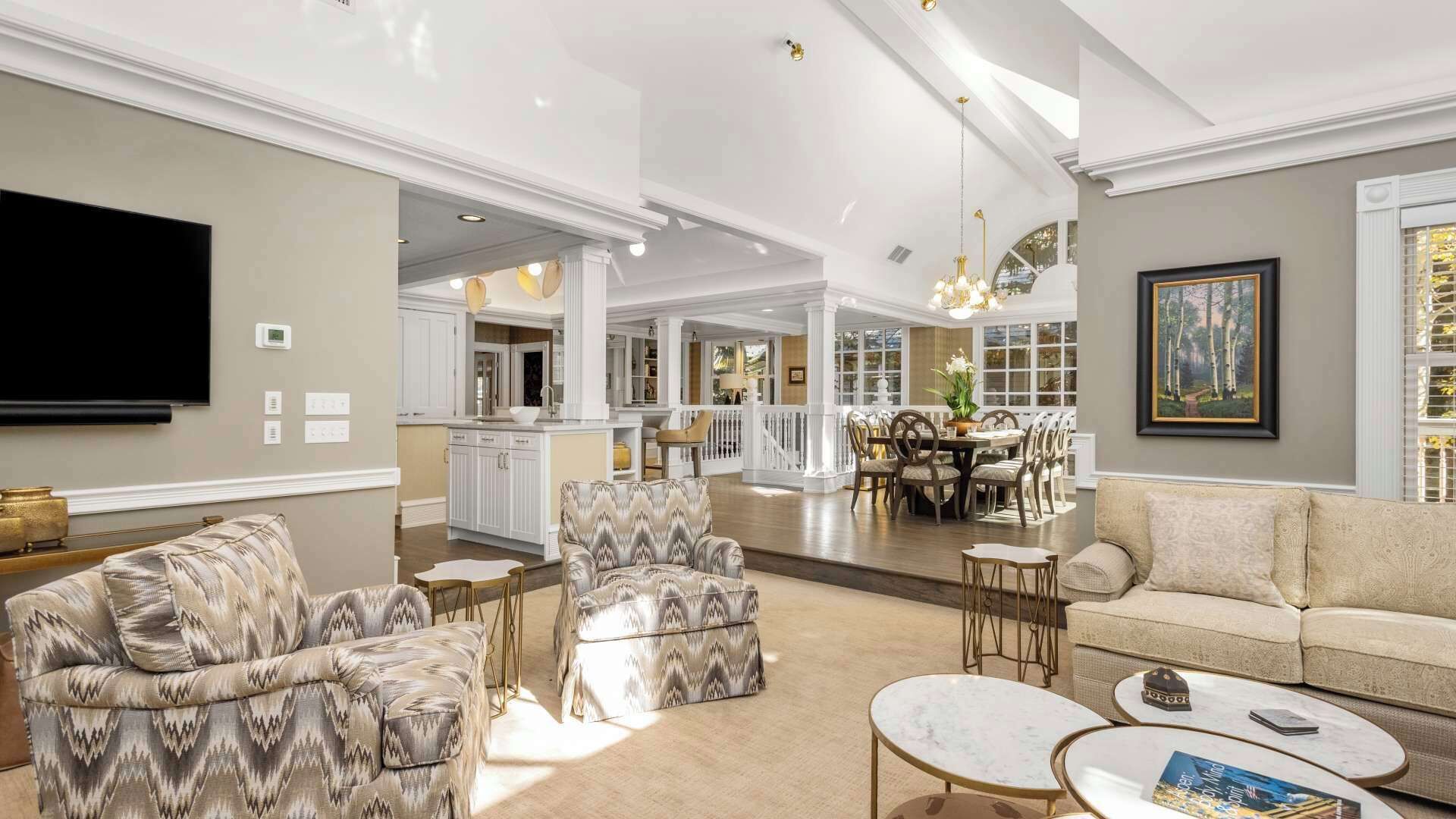 Un salón amplio con una televisión grande, asientos cómodos y una zona de comedor al fondo.