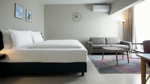 A modern hotel room with a bed, a sofa, a small table, and a clock on the wall. - Nordic Hotel Lagos (Victoria Island)