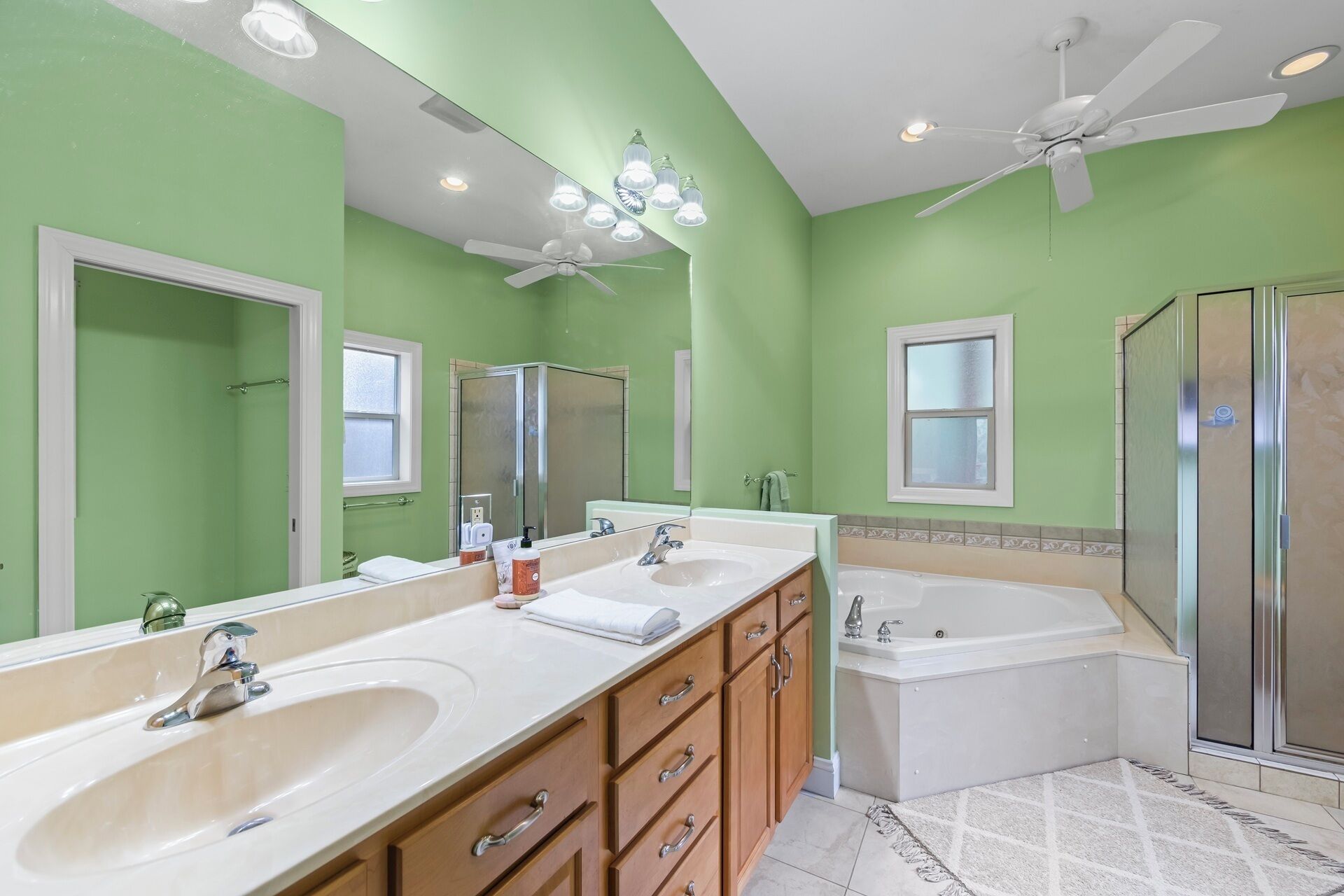 A bathroom with two sinks, a bathtub, a shower, and a ceiling fan.