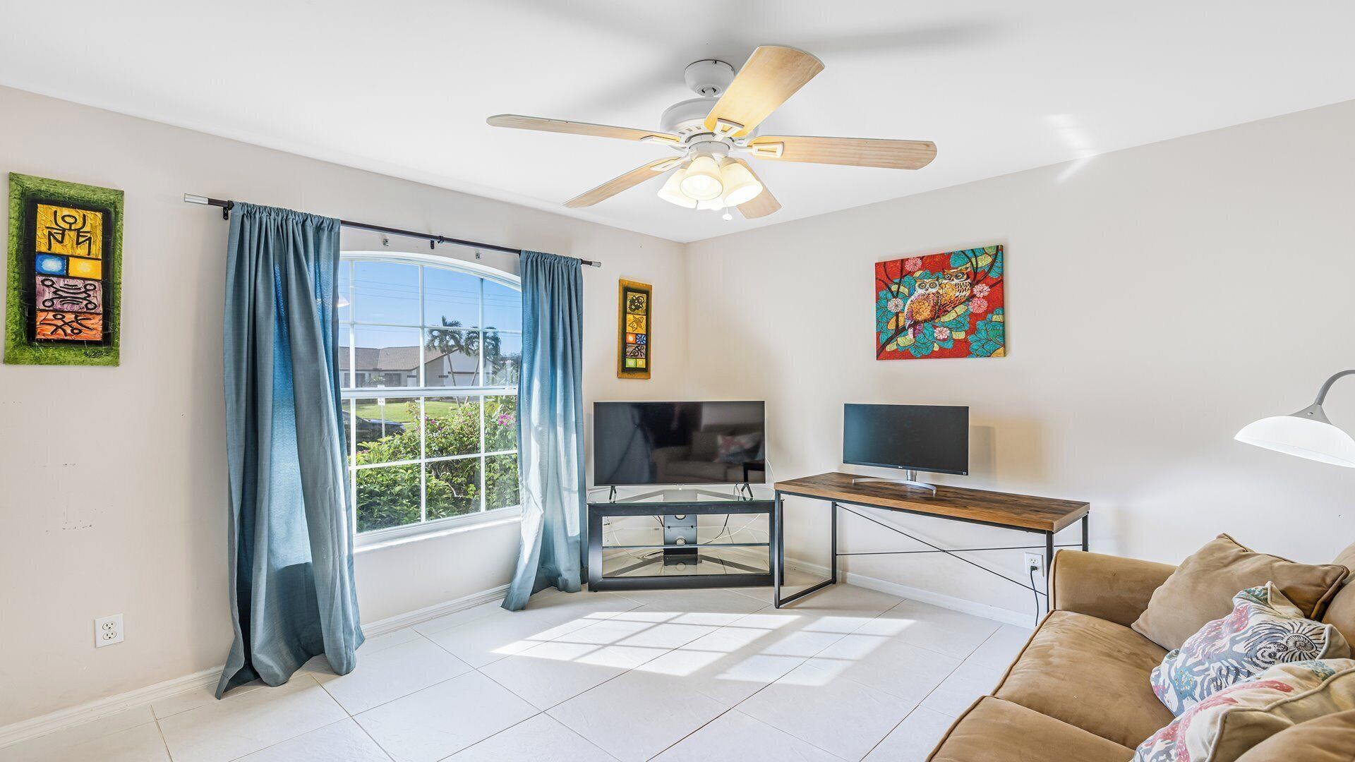 A living room with a ceiling fan, a TV, a glass-top coffee table, and a couch.