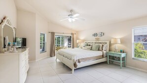 A bedroom with a bed, a ceiling fan, a dresser, a nightstand, and a window with blinds.
