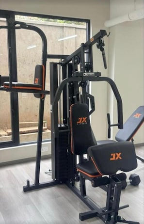 Une salle de sport équipée de machines de musculation, de bancs et dotée d’une fenêtre donnant sur l’extérieur.