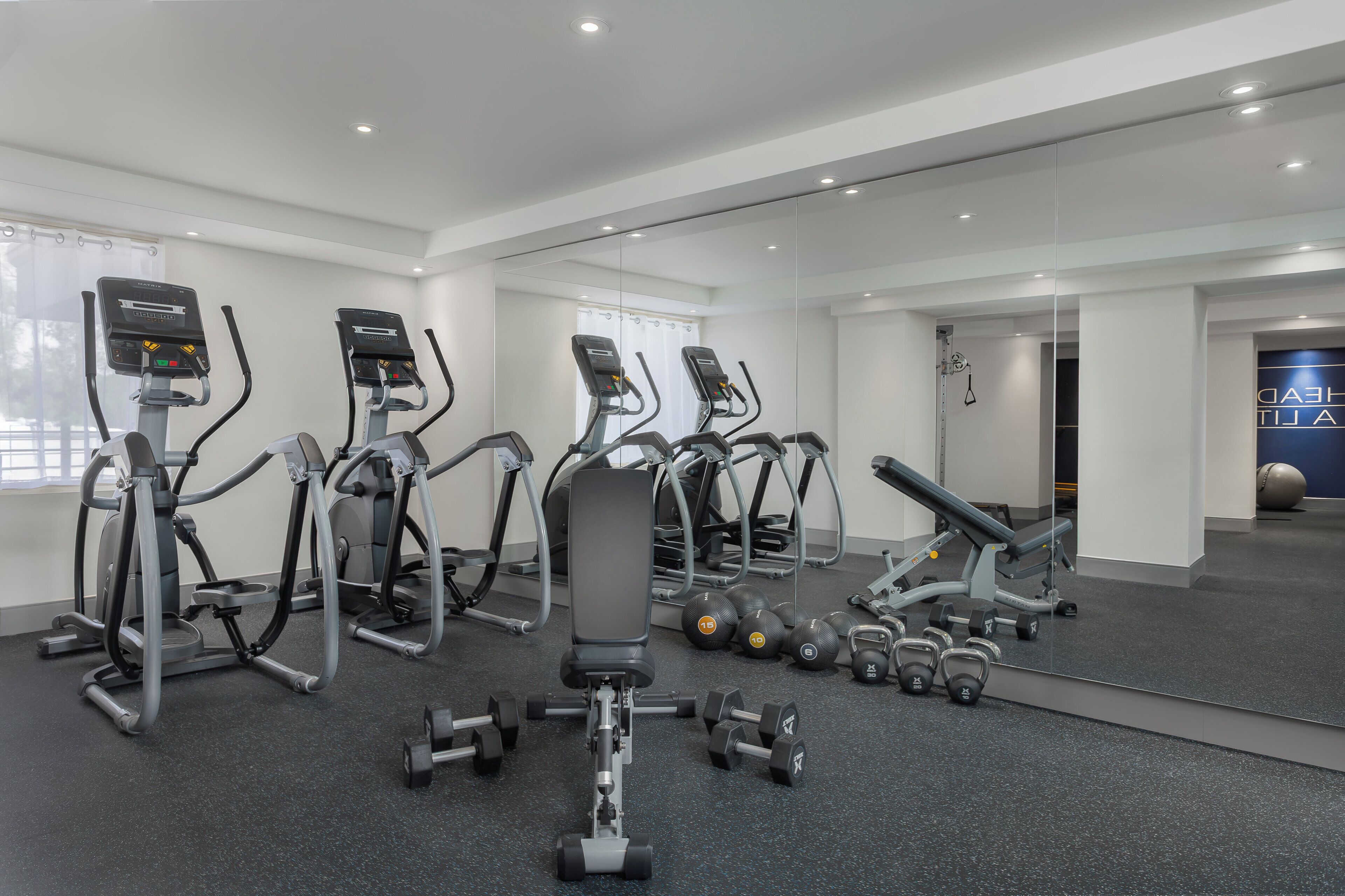 Un gimnasio con cintas de correr, elípticas y pesas sueltas.