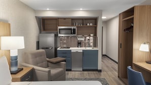 A compact hotel room with a kitchenette, a bed, a desk, and a chair. - Candlewood Suites Chatham South by IHG (Chatham)