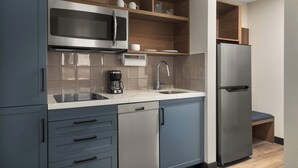 A modern kitchen with stainless steel appliances, grey cabinetry, and a wooden shelf. - Candlewood Suites Chatham South by IHG (Chatham)