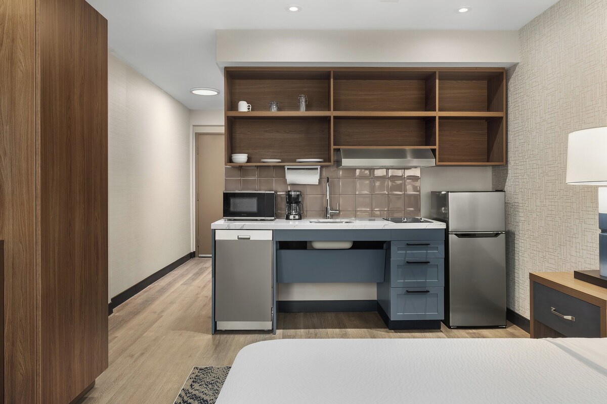 Habitación de hotel compacta con kitchenette, que incluye microondas, cafetera, fregadero y refrigerador.