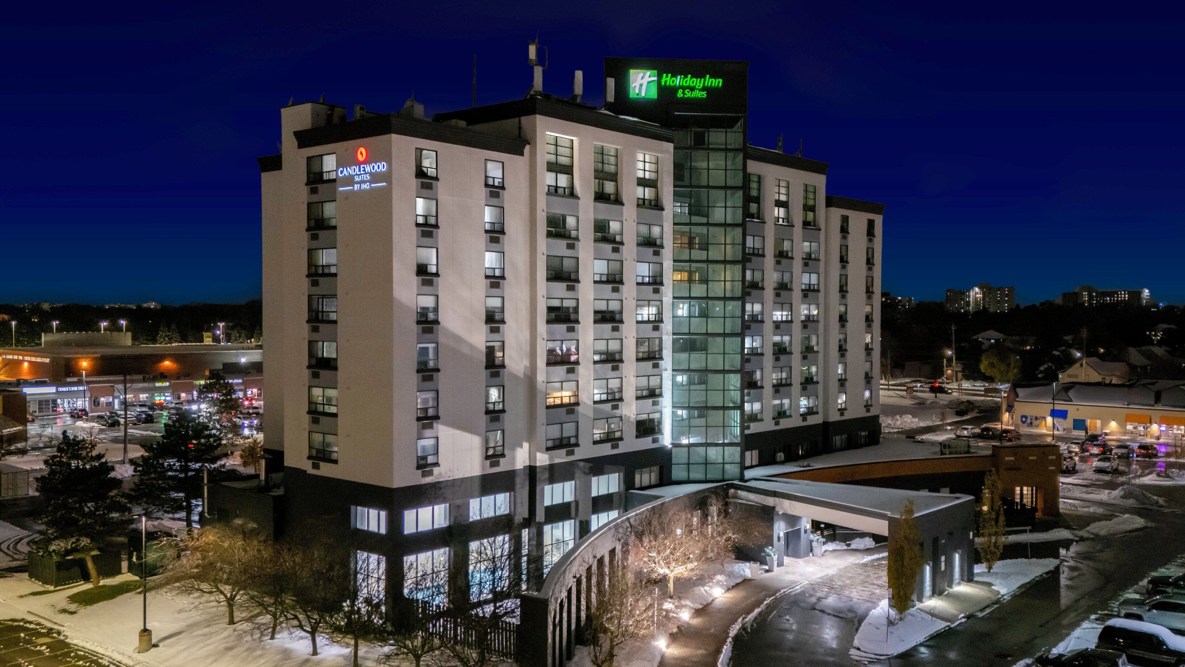 Un hotel de varios pisos con un letrero de Holiday Inn, que presenta un diseño arquitectónico moderno con grandes ventanales y una entrada destacada.