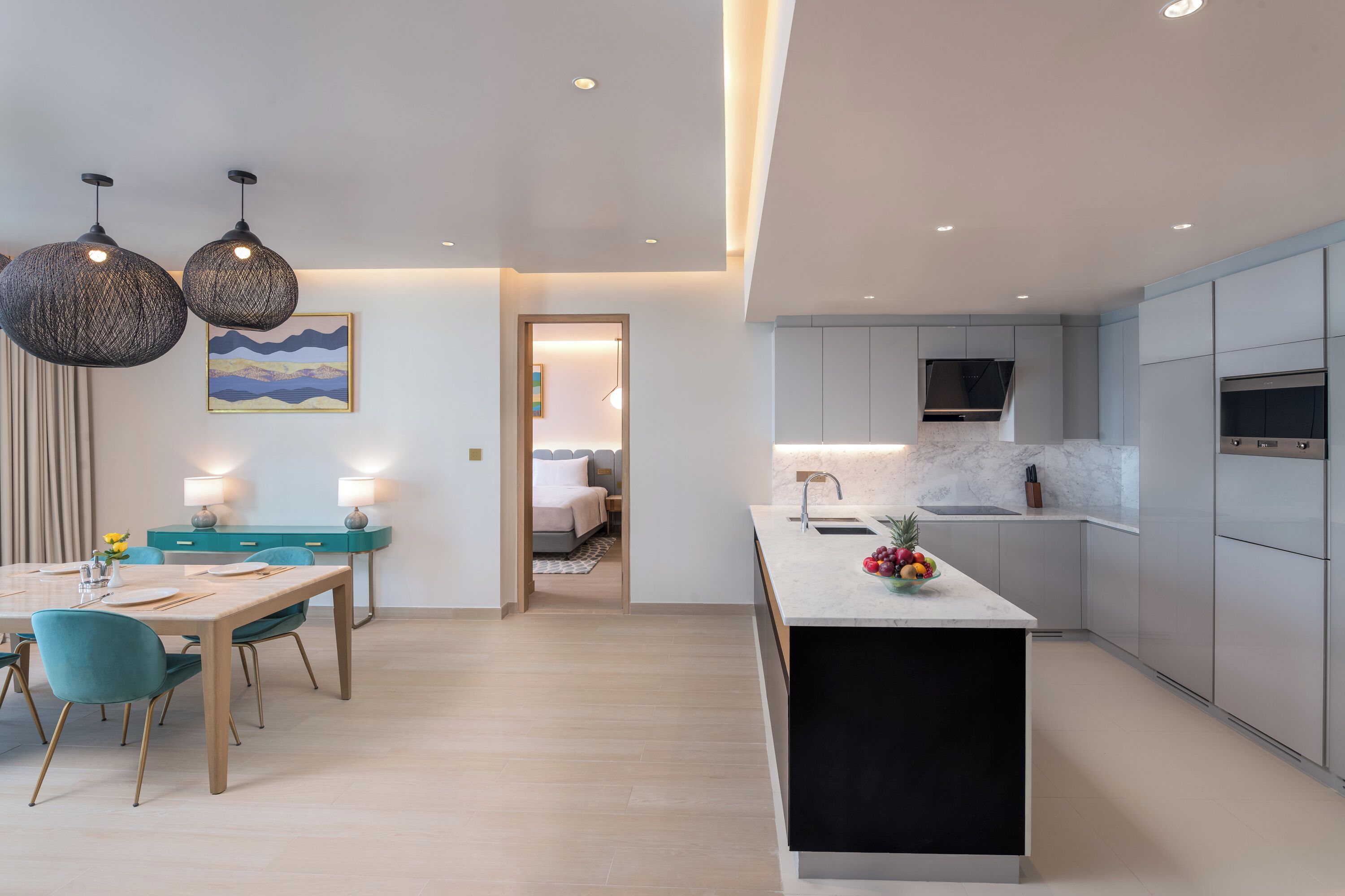 A modern kitchen with a marble countertop, a built-in oven, and a sink.