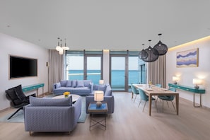 A modern living room with a sofa, armchairs, a coffee table, a TV, and a dining area with a table and chairs. - voco Muscat Al Mouj by IHG (Muscat)