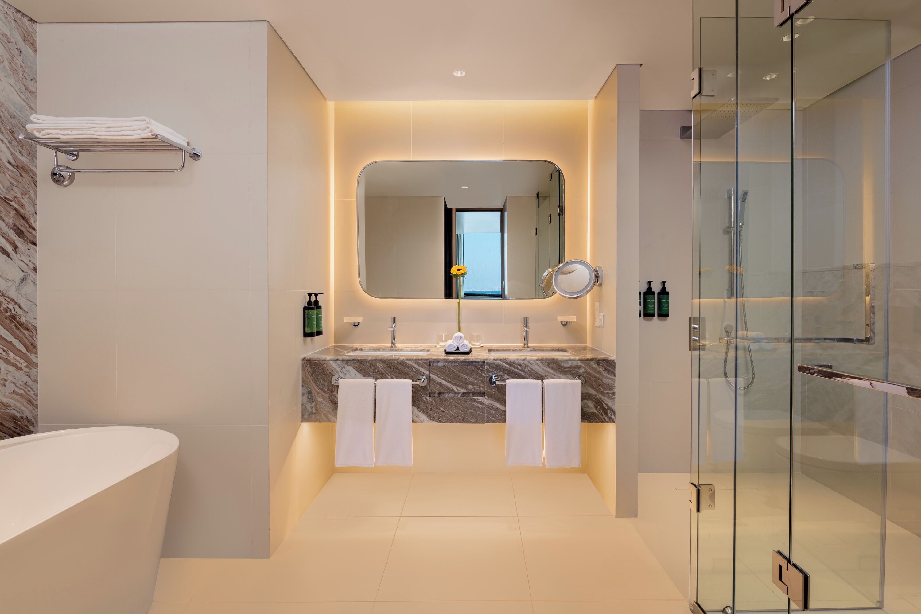 A modern bathroom with a marble vanity, a large mirror, and a glass-enclosed shower.