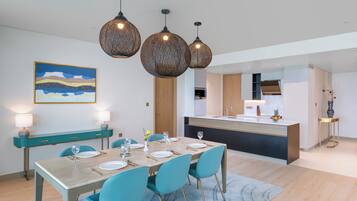 A modern dining area with a wooden table, teal chairs, and pendant lighting.