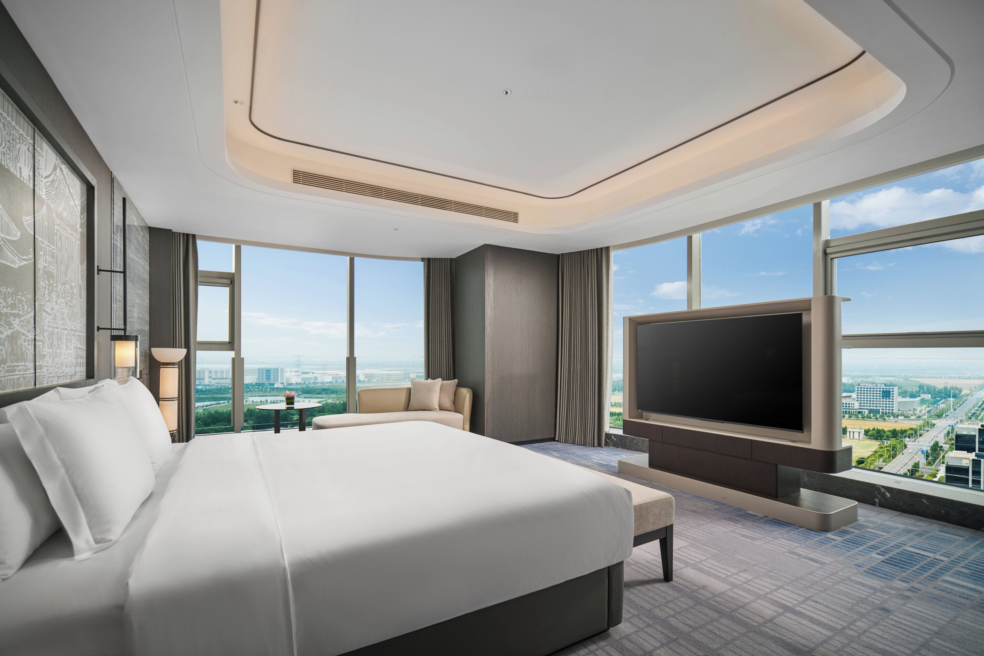 Habitación de hotel moderna con una cama grande, un televisor de pantalla plana y vista a la ciudad.