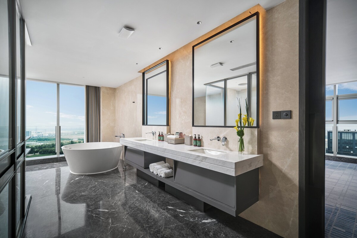 Une salle de bain moderne avec une grande baignoire, deux lavabos et un grand miroir.