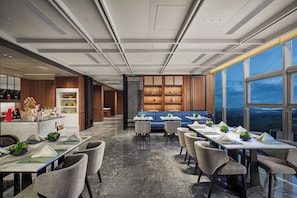 A modern dining area with a long table, chairs, and a blue sofa.