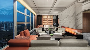 En moderne lounge med udsigt over byen, behagelige siddepladser og en pejs.