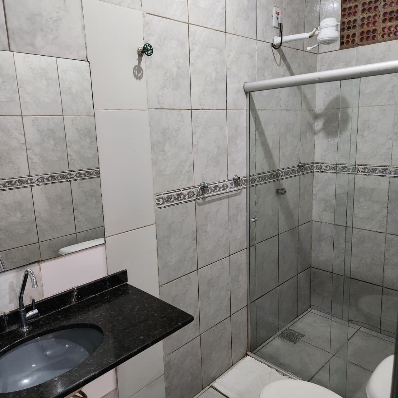 Une salle de bain avec douche, toilettes et lavabo.