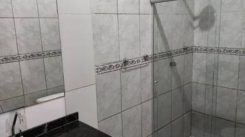 Une salle de bain avec douche, toilettes et lavabo.