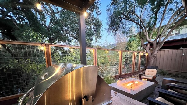 Una veranda esterna con barbecue integrato, area salotto e luci decorative.