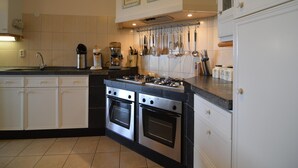 A kitchen with two stainless steel ovens, a coffee maker, and a set of hanging utensils. - Holiday Home in Noordbeemster With Bubble Bath (Noordbeemster)