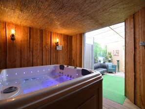 Una habitación de madera con un jacuzzi, paredes de madera y un ventanal corredero que da a un espacio exterior.